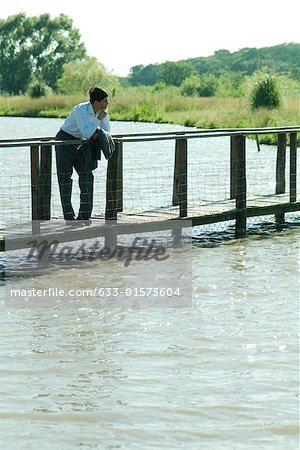 Homme d'affaires sur une passerelle en bois au-dessus du lac, à la recherche de suite