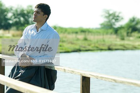 Homme d'affaires sur une passerelle en bois au-dessus du lac, à la recherche de suite