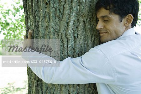 Businessman hugging tree