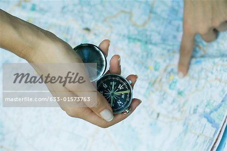 Woman pointing to map and holding compass, close-up