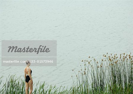 Young woman in swimsuit standing by edge of water