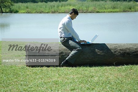 Businessman sitting on log, using laZSop