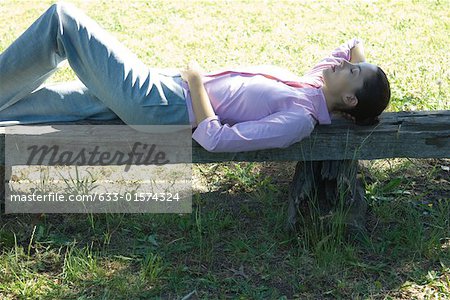 Businesswoman lying on bench, eyes closed