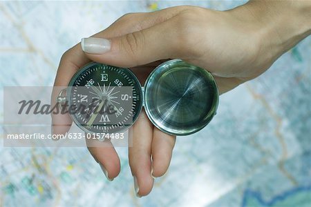 Woman's hand holding compass, map in background