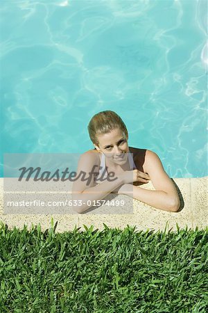 Jeune femme au repos de bras sur le bord de la piscine