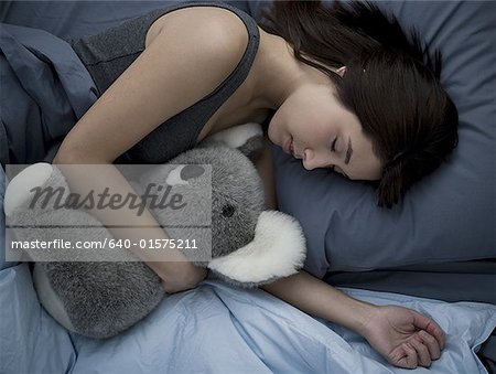 Femme allongée dans son lit avec animal en peluche