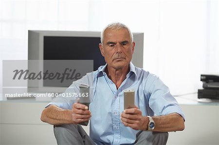 Homme regardant les télécommandes de télévision