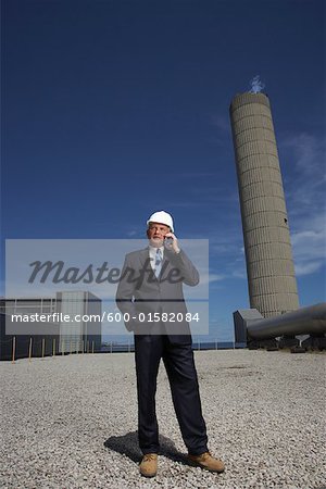 Homme d'affaires à l'extérieur de l'usine avec un téléphone cellulaire