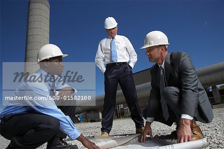 Businessmen Looking at Blueprint Outside of Factory