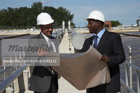 Businessmen Looking at Blueprint Outside Water Treatment Plant