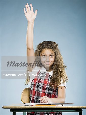 Schoolgirl at desk with arm raised