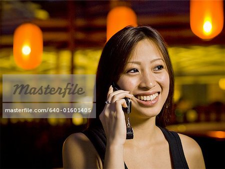 Woman talking on a cell phone outdoors at night smiling