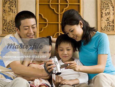 Parents looking at video recorder with son and daughter