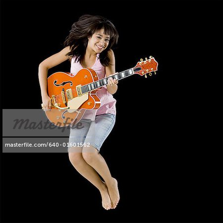 Woman with guitar leaping and smiling