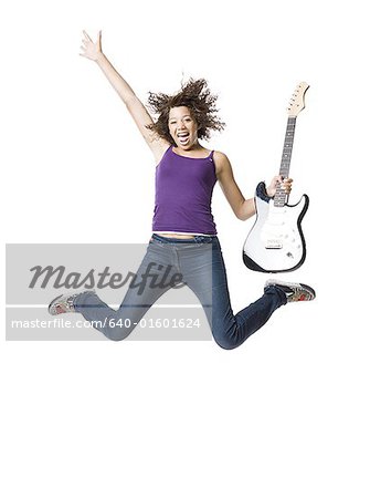 Girl with electric guitar jumping and smiling with arm up