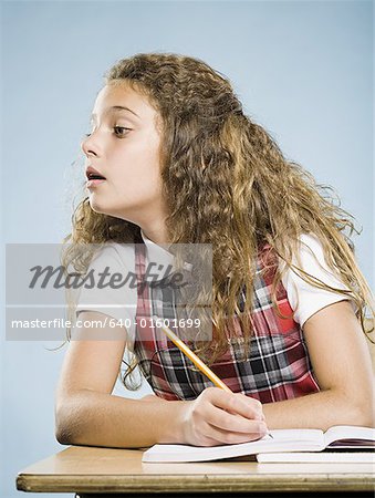 Girl sitting at desk with workbook looking over