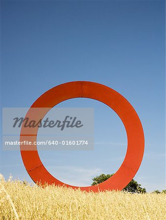 Giant red O in field with blue sky