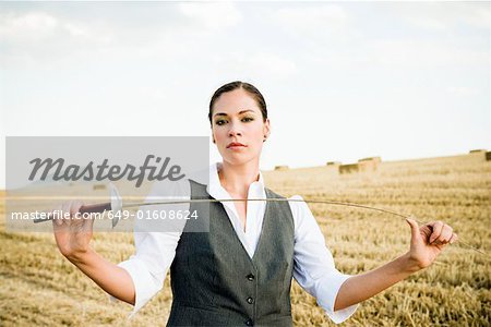 Femme d'affaires d'escrime dans un champ de blé.