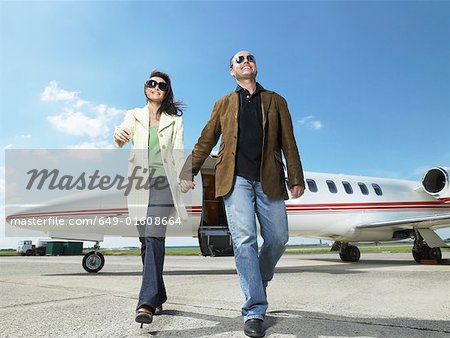 Happy couple walking away from private jet.