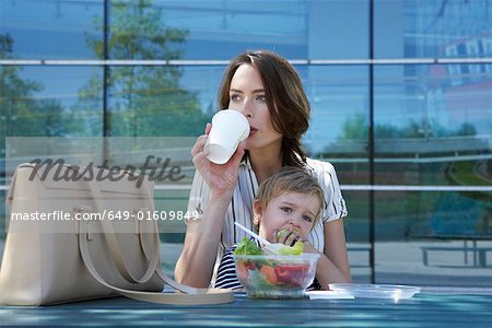 Businesswoman and her child eating lunch together outside.