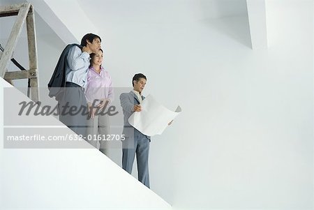 Young couple standing with architect, overlooking spacious interior