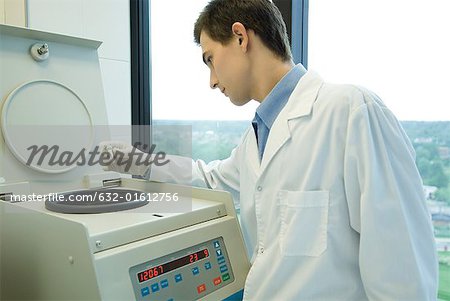Young male scientist using centrifuge