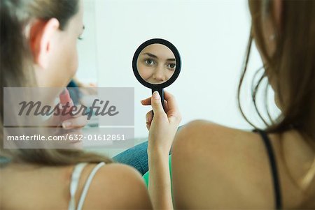 Teenager-Mädchen sitzt neben Freund, Anwenden von Lippenstift, betrachten selbst in der hand Spiegel, Rückansicht