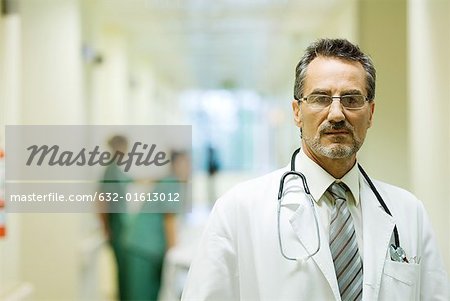 Médecin de sexe masculin debout dans le couloir de l'hôpital, en regardant la caméra, tête et épaules