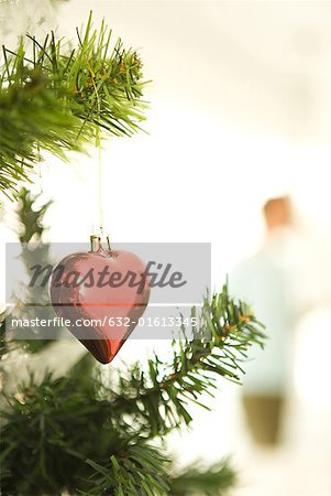 Heart shaped Christmas ornament hanging on Christmas tree, cropped view