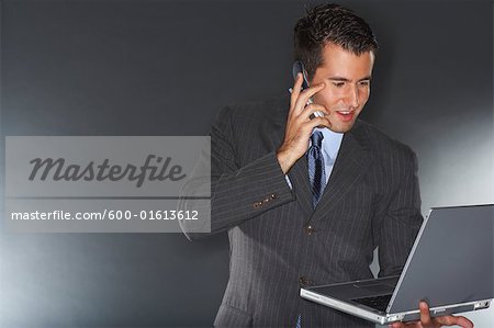 Businessman Using Laptop and Cellular Phone