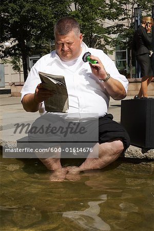 Businessman Reading Newspaper in Wading Pool