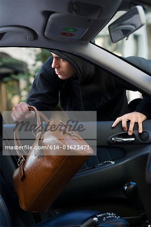 Un voleur vole un sac d'une voiture