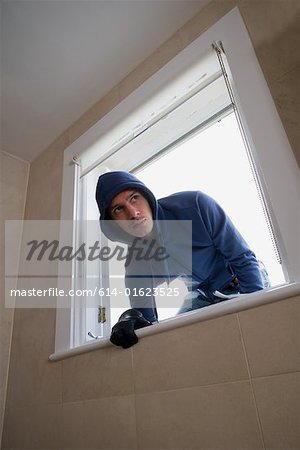 Ein Einbrecher steigen durch ein Fenster
