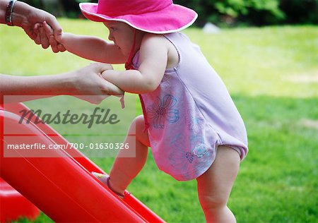 Baby Girl Being Helped Up Slide By Mother