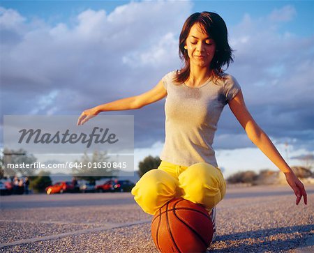 Young woman kneeling on basketball