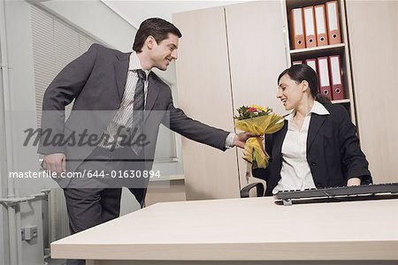 Männlichen Büroangestellten erteile Kollegin Blumen