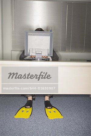 Employé de bureau devant un ordinateur portant des palmes de natation
