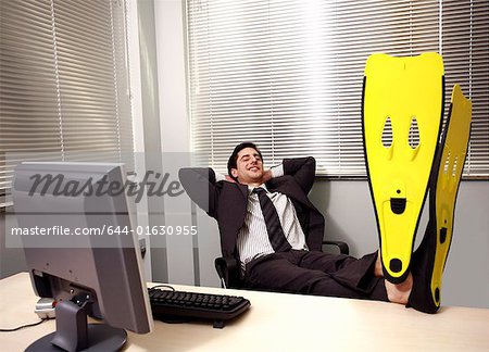 Büroangestellter am Computer Schwimmflossen tragen