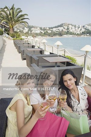 Three women with shopping bags toasting