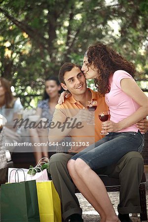 Frau sitzt auf dem Schoß des Mannes mit Einkaufstüten im cafe