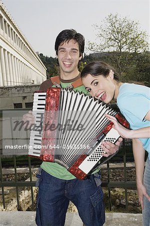 Man playing accordion with woman smiling