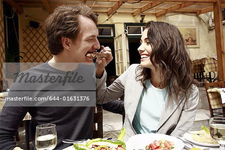 Woman feeding man a lamb chop