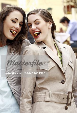 Two women posing with an olive in their mouths