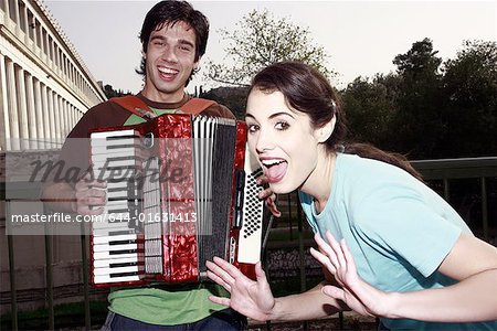 Man playing accordion, woman posing