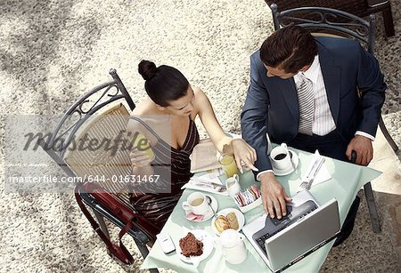 Couple d'affaires dans le café-jardin avec ordinateur portable