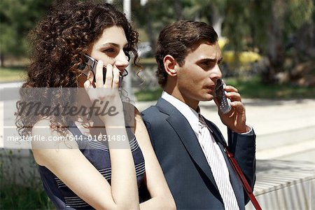 Businessman and businesswoman on cell phones