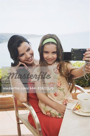 Mère et fille au café de bord de mer avec caméra