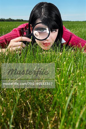 Femme examinant l'herbe avec loupe