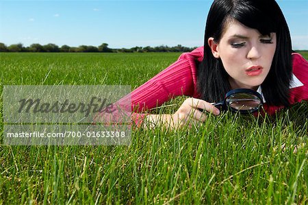 Femme examinant l'herbe avec loupe