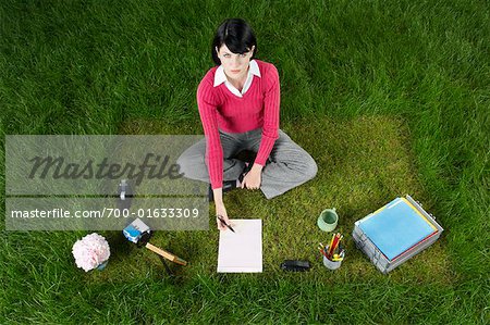 Geschäftsfrau, die auf Gras zu sitzen